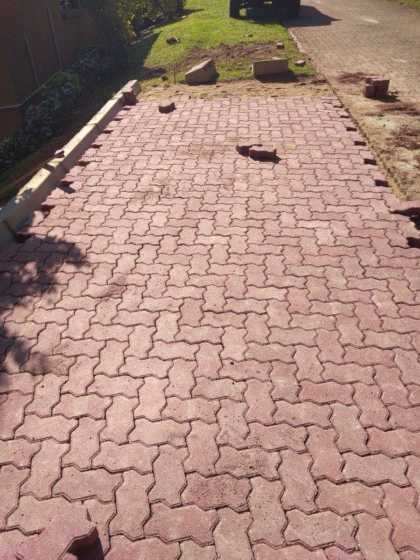 Red interlocking pavers being laid on residential driveway